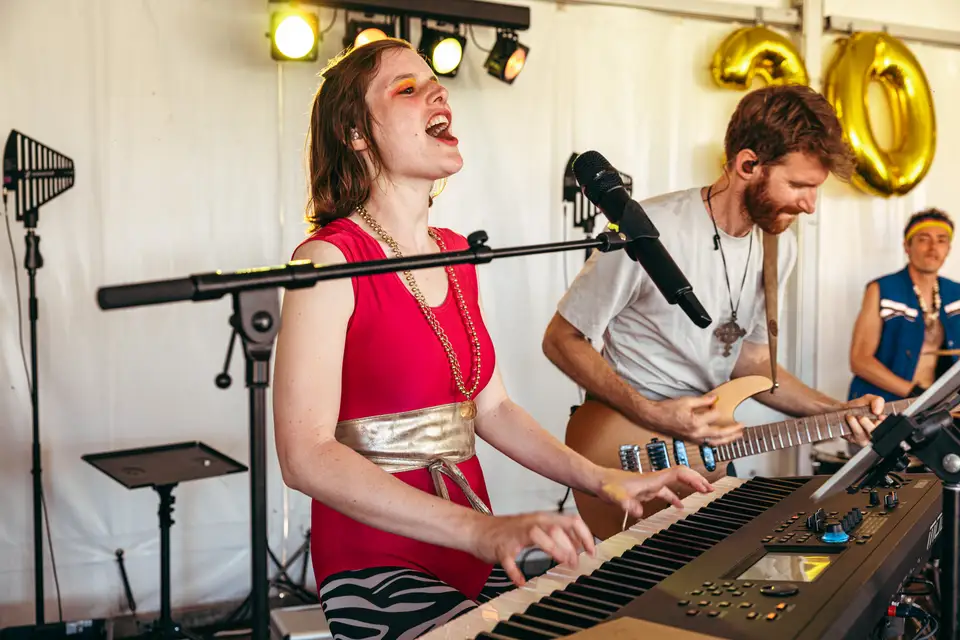 Singer-keyboardist Gentle Riverstar and lead guitarist Cpt. Lee Bido perform with 80s party coverband Radio Spandex at a private 30th birthday celebration in a festive tent decorated with large gold balloons.