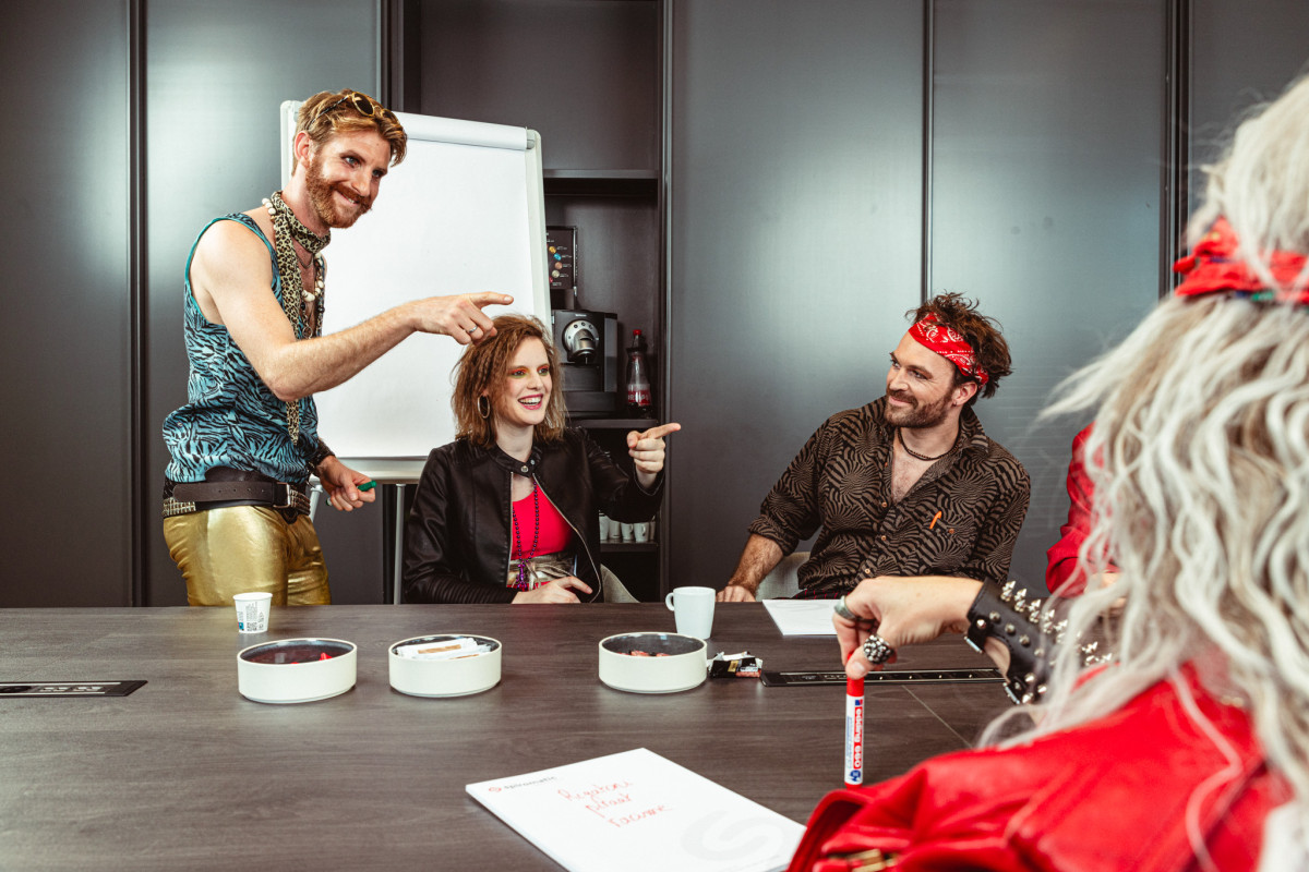 Group photo of 80s cover band Radio Spandex in a meeting room, joyfully engaged during a training session