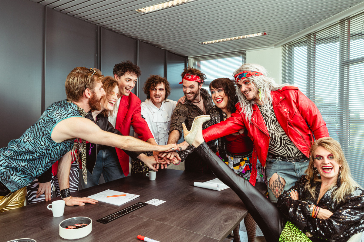 Group picture of 80's cover band Radio Spandex in a meeting room celebrating with high fives
