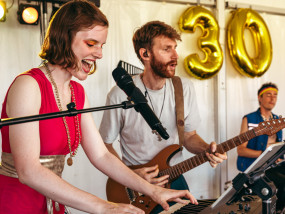 Gentle Riverstar & Ctp. Lee Bido gaan helemaal los — © Michiel Devijver Gentle Riverstar playing keyboard with Ctp. Lee Bido on guitar performing on stage with 80's coverband Radio Spandex at a birthday party. - Michiel Devijver Photography